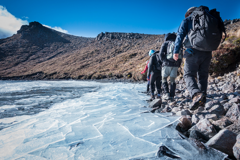 Walking on the shoe of Upper Tama Lake with sheets of ice broken by wind over the water