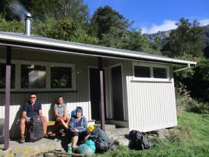 Trampers resting outside Waipawa Forks Hut in the Ruahine Ranges