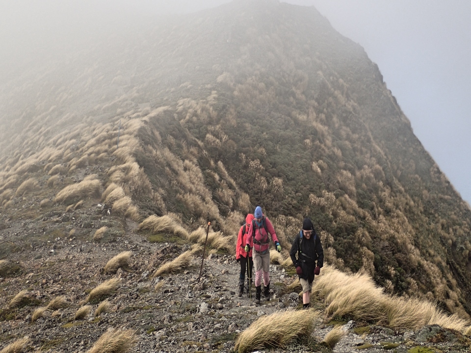 Trampers walking along a ridge in windy conditions