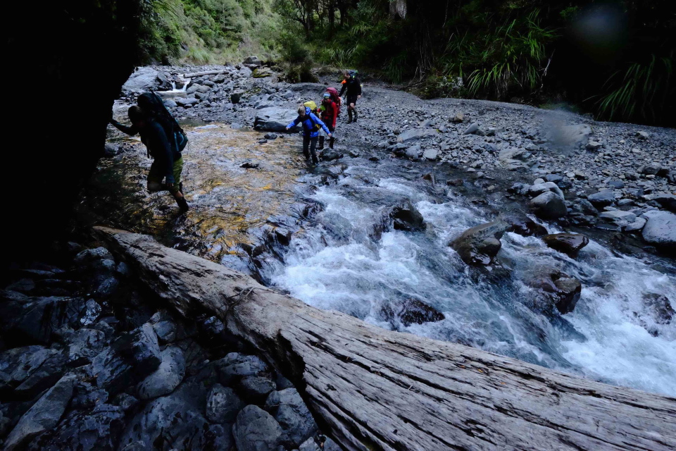 Trampers crossing a river between Black Ridge and Daphne Hut