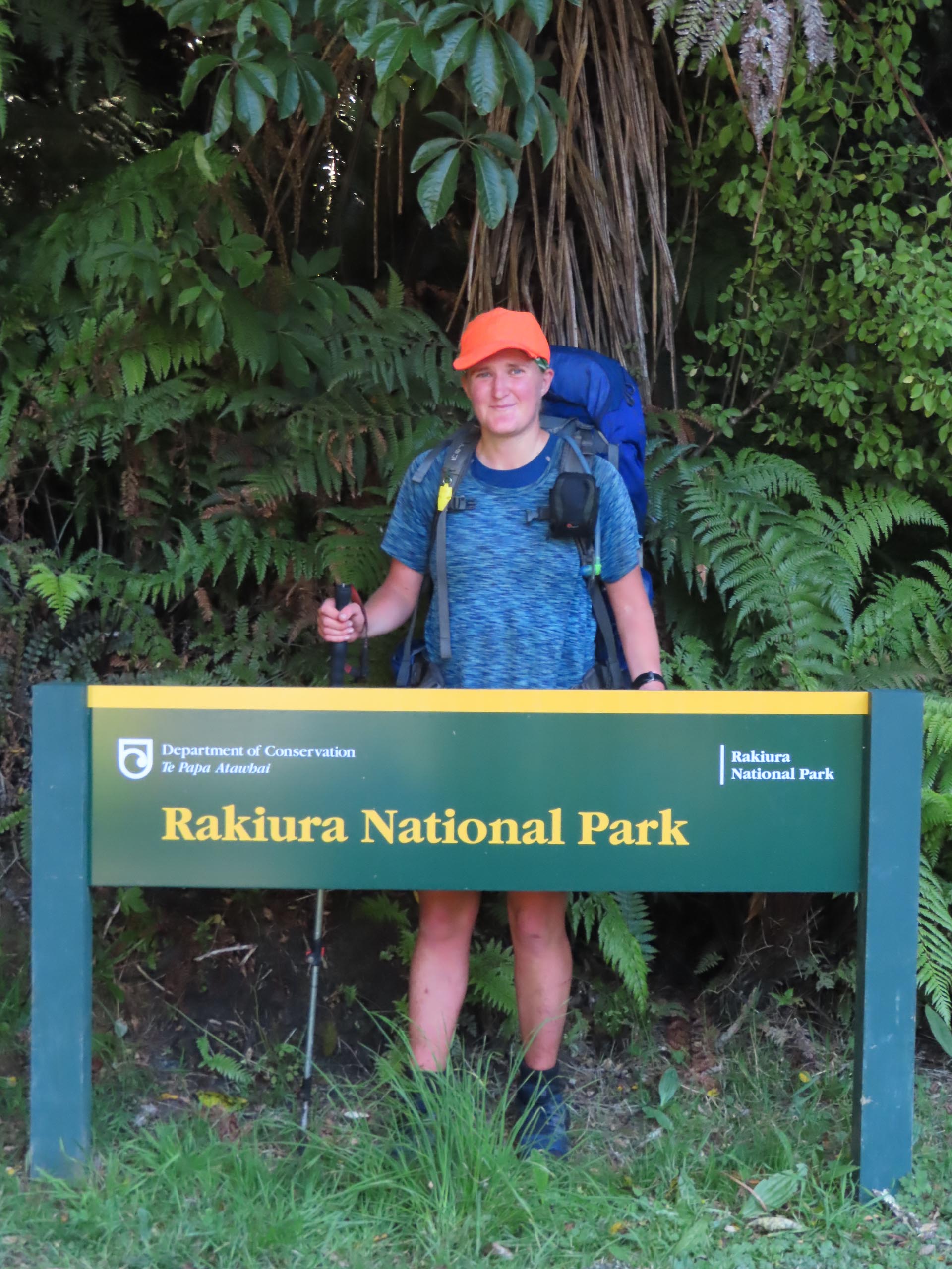 Sarah stands by the DOC sign at the end of her 12 day solo trip in Rakiura National Park