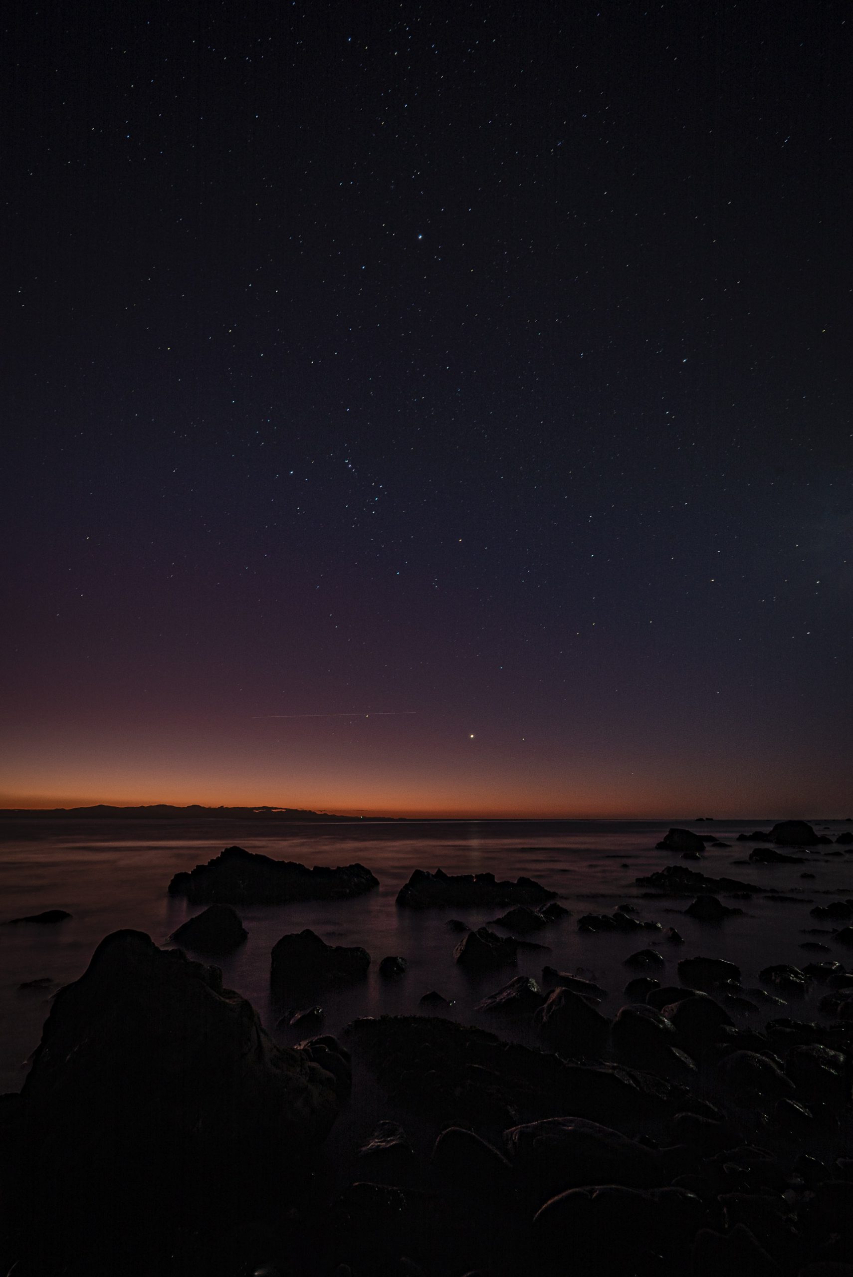 The planet Venus and the constellation of Orion above the glassy sea