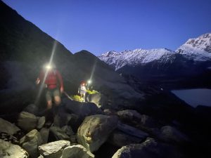 photo of people walking in the dark with headtorches through rocks
